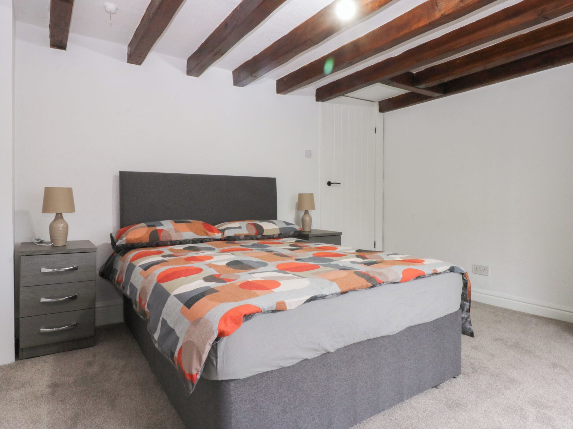 Un dormitorio con una cama, dos mesitas de noche y una puerta.