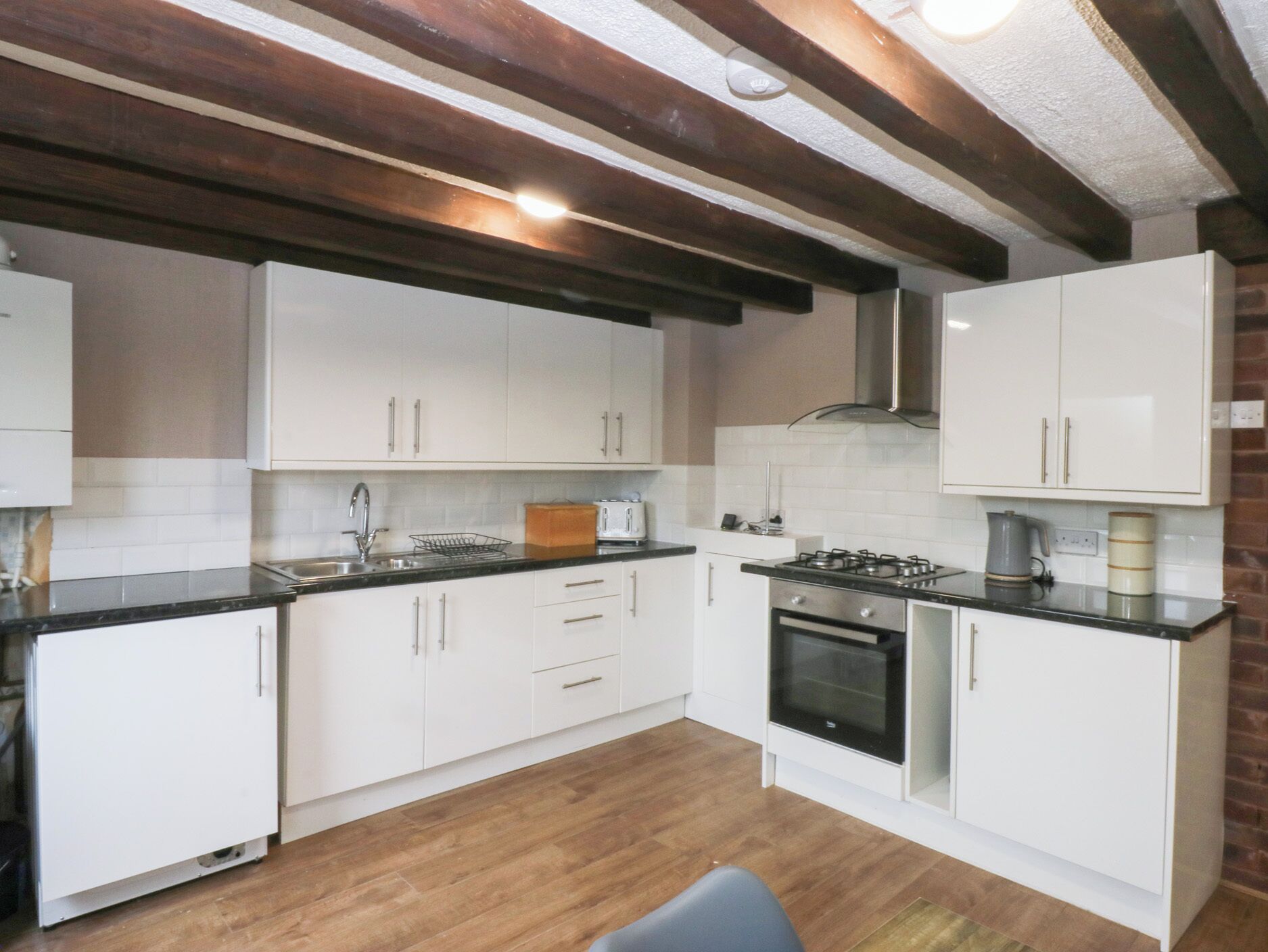 A kitchen with white cabinets, a black countertop, a stove, and a sink.