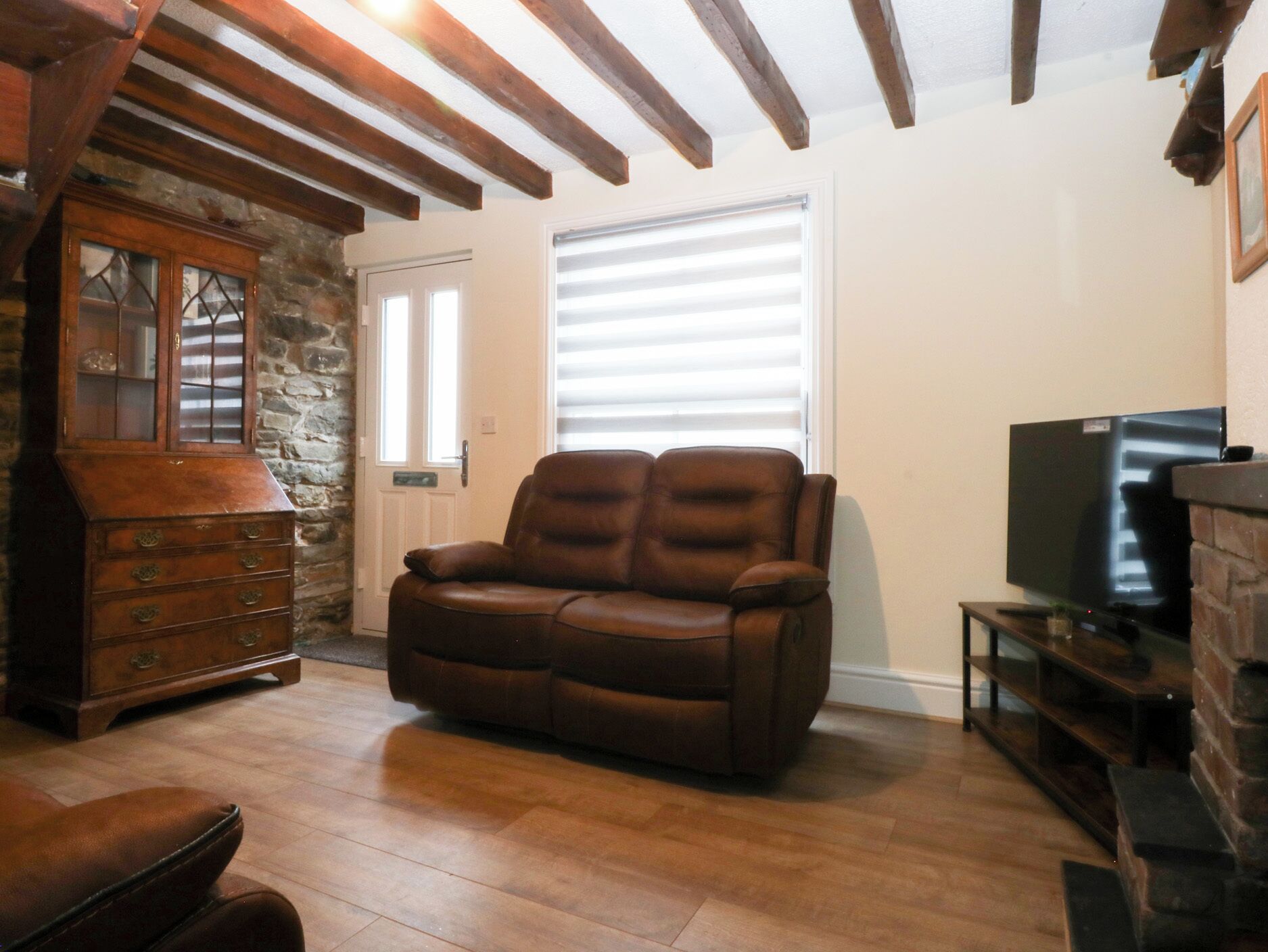 Un salon avec un canapé en cuir, un meuble en bois et un téléviseur.