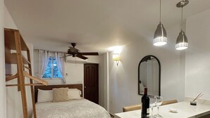 Une chambre à coucher avec un lit, une échelle en bois, un bureau avec une chaise et un miroir.