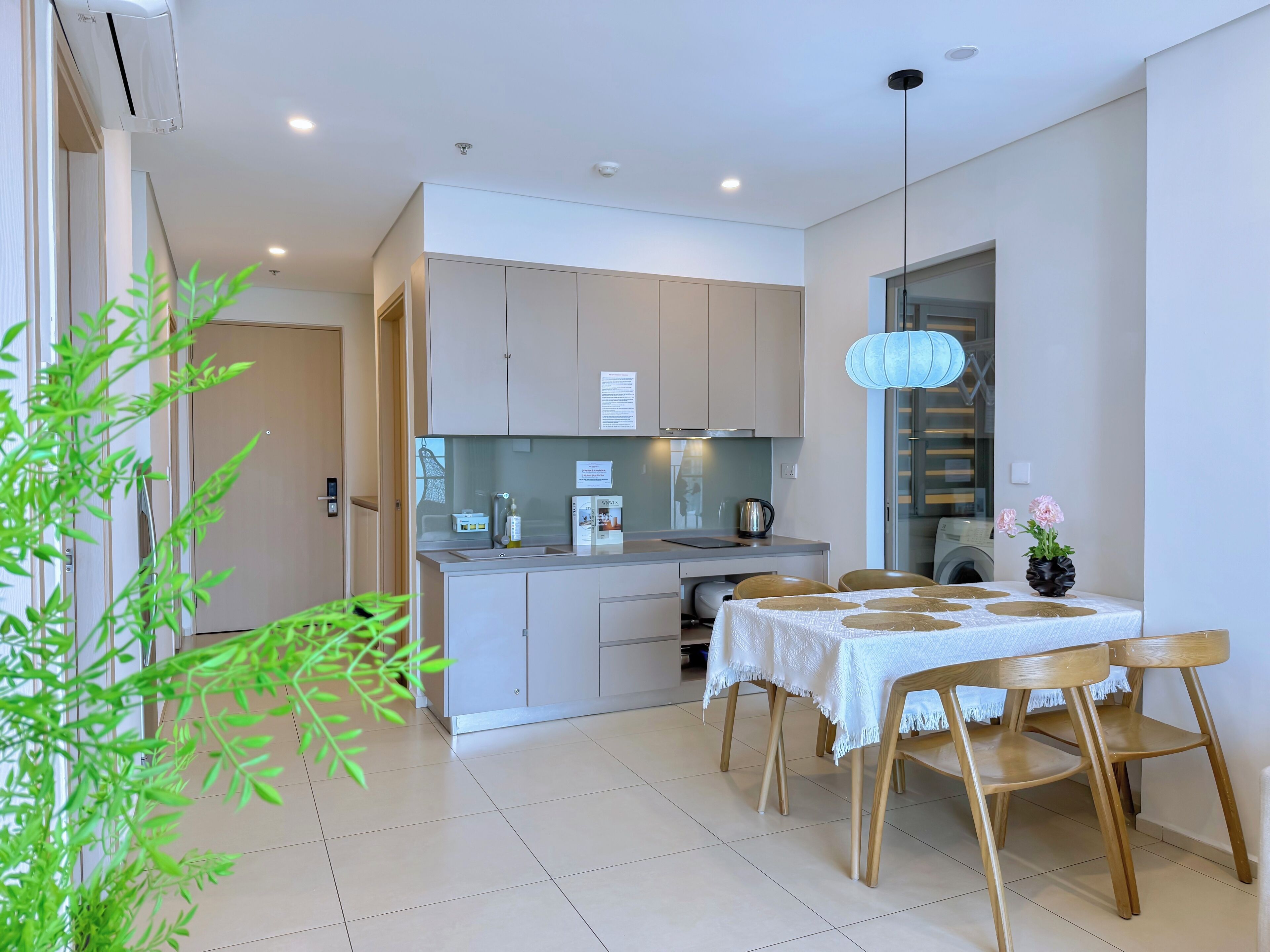 Una cocina moderna con comedor, que incluye una mesa con sillas, una lámpara colgante y una planta en maceta.