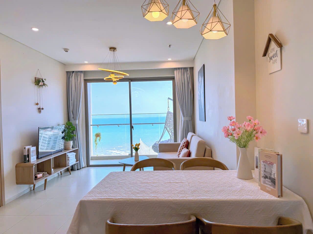 Una habitación de hotel moderna con una cama, una mesa de comedor, un televisor y un balcón con vista al mar.