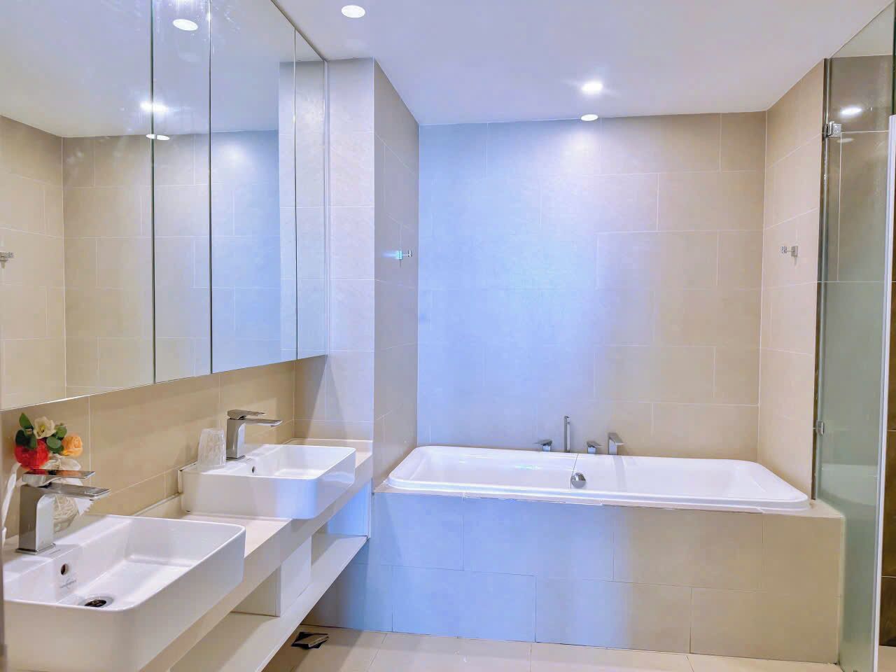 Un baño moderno con dos lavamanos, una bañera y un espejo grande.