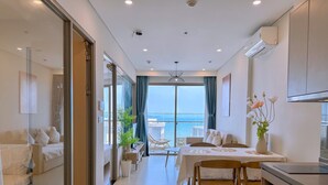 A modern hotel room with a balcony, a dining area, and a kitchenette. - THE SÓNG Apartment Vũng Tàu - ViVi Home (Ho Chi Minh City)
