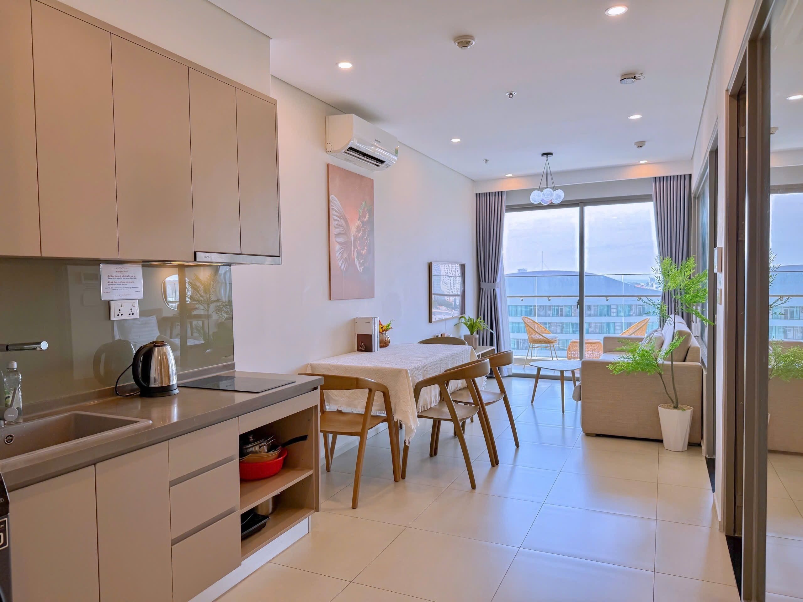 A modern kitchen with a dining area, a view of the city, and a balcony with plants.