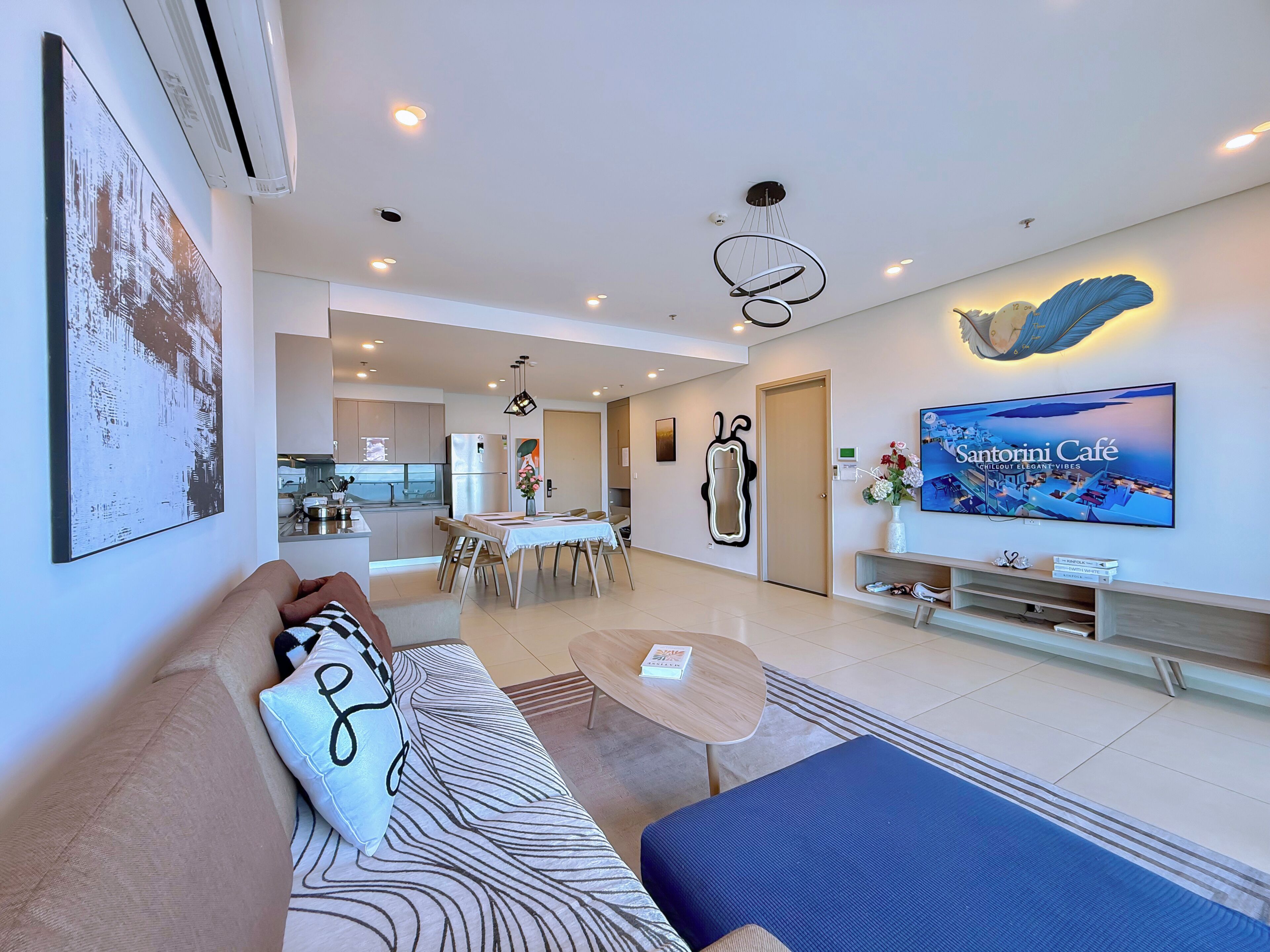 A modern living room with a sofa, coffee table, and a TV displaying 'Santorini Café'.