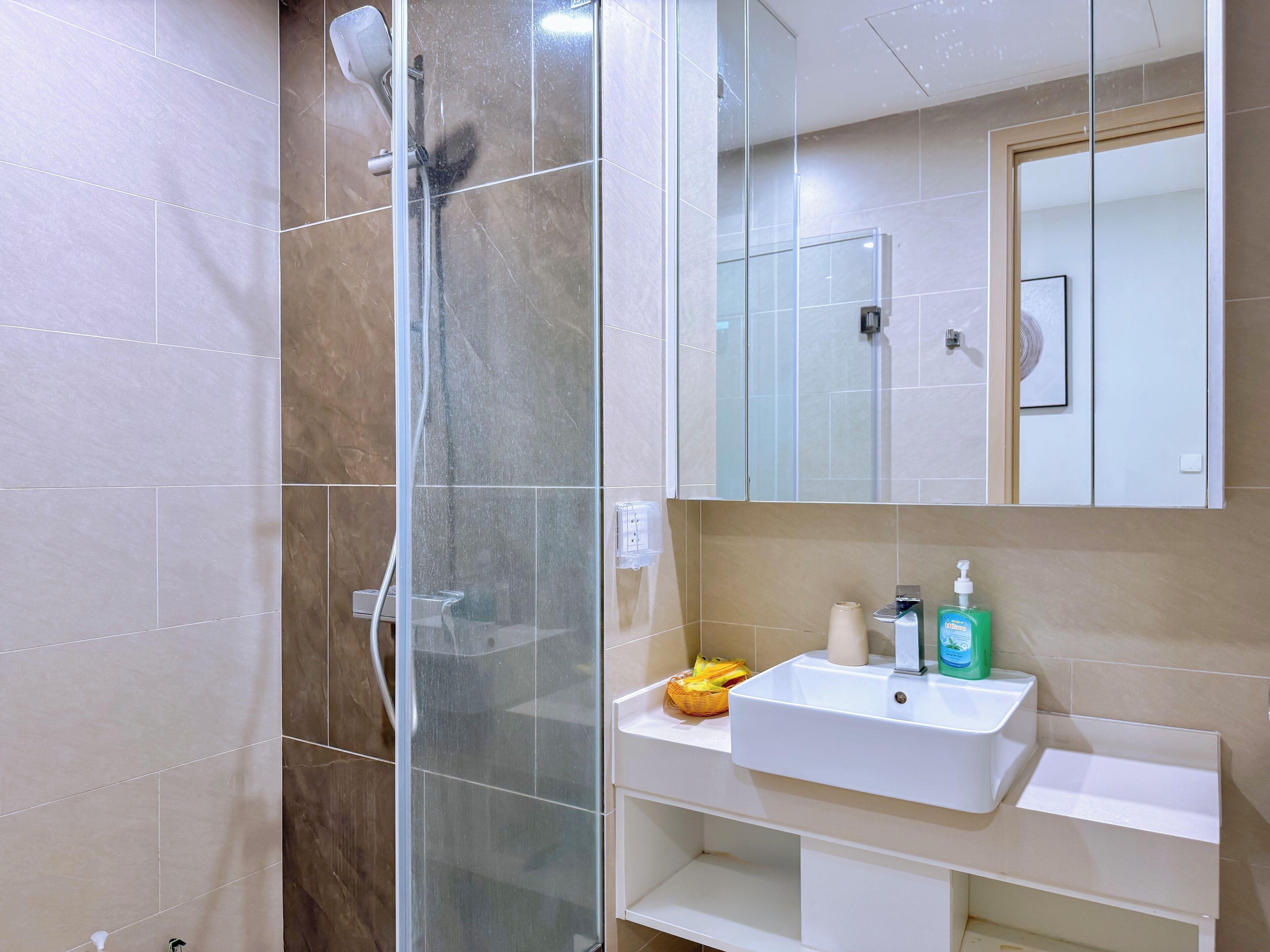 Un baño con cabina de ducha de vidrio, un lavabo blanco y un espejo sobre el lavabo.