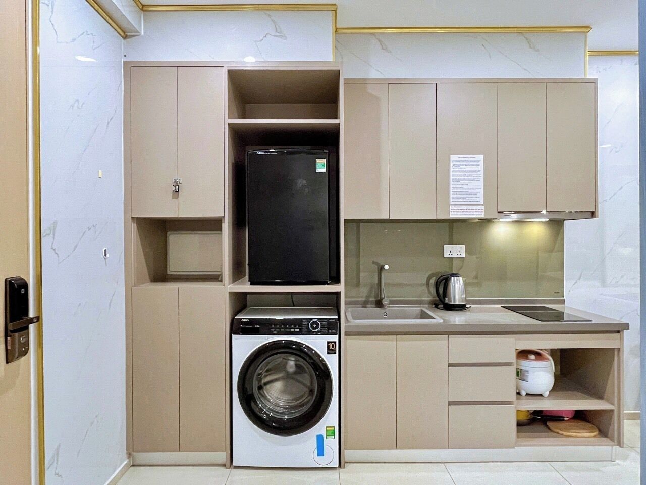 A compact kitchen with built-in appliances, including a washing machine, a microwave, and a refrigerator.