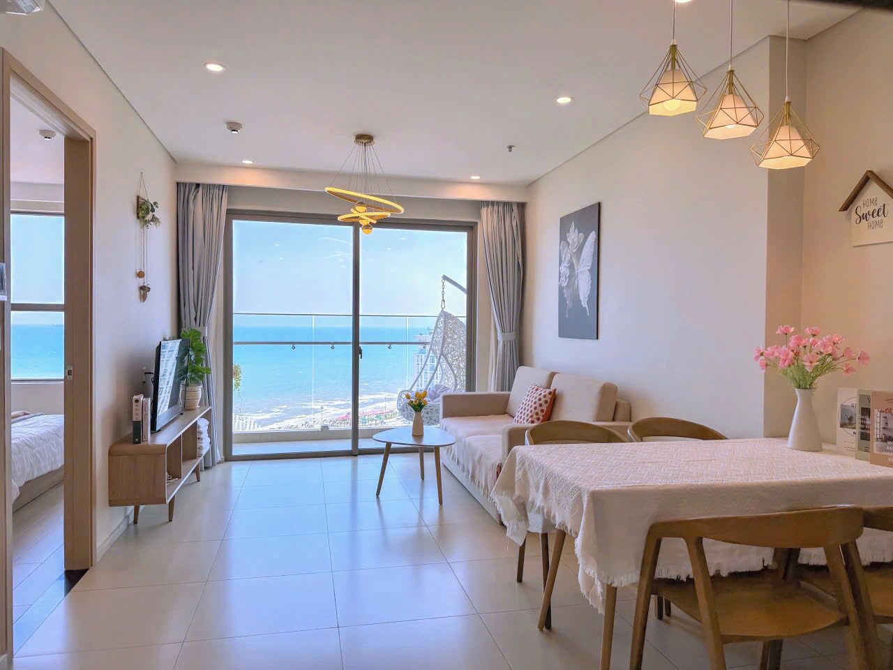 A modern living room with a balcony, a dining area, and a view of the sea.