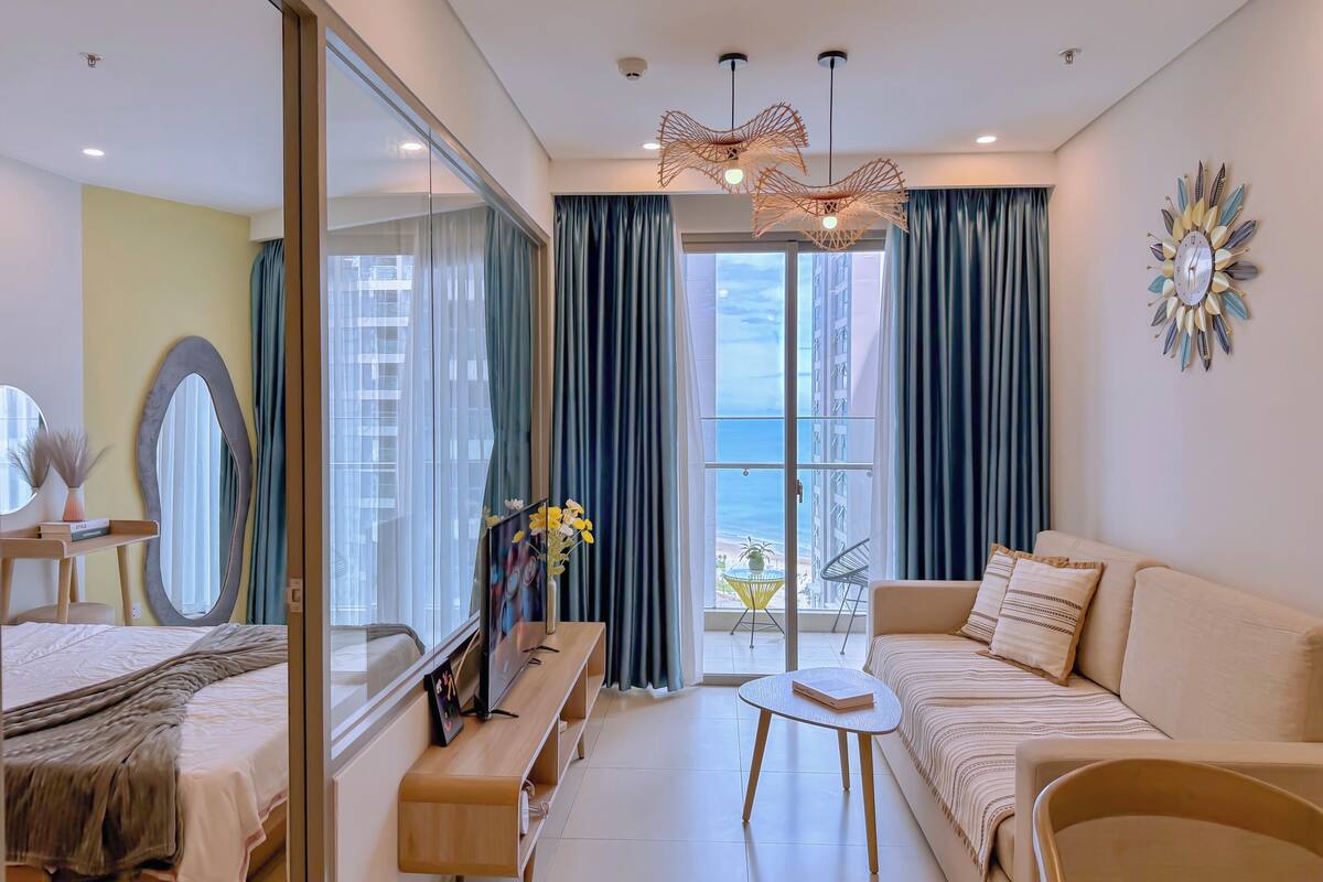 Une chambre d’hôtel moderne équipée d’un lit, d’un canapé, d’une table ronde et d’un balcon avec des rideaux.