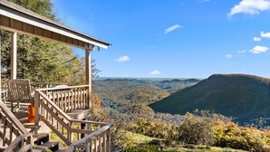 A wooden deck with a chair and a bottle, overlooking a mountainous landscape. - Tiger Ridge, Single Level w/ Stunning Mtn Views (Highlands)