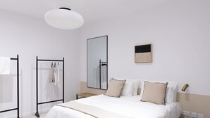 Ein modernes Schlafzimmer mit einem großen Bett, einem Kleiderschrank, einem Spiegel und einem Nachttisch.