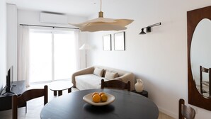 Ein moderner Essbereich mit einem runden Tisch, einer Obstschale und einer Couch im Hintergrund.