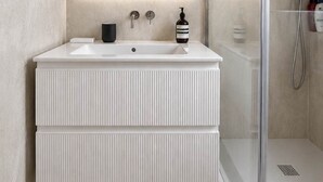 A modern bathroom with a large mirror, a white vanity, a shower enclosure, and a glass shower door. - Notting Hill Views (London)