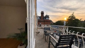 A balcony with a view of a building with a dome and chimney, outdoor furniture, and a potted plant. - Notting Hill Views (London)