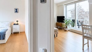 A spacious living area with a large window, a television, a sofa, and a dining table. - Notting Hill Views (London)