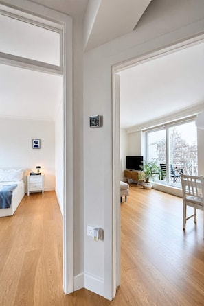 A spacious living area with a large window, a television, a sofa, and a dining table. - Notting Hill Views (London)