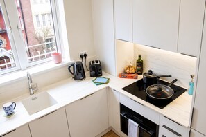 A modern kitchen with a sink, kettle, toaster, and stove. - Notting Hill Views (London)