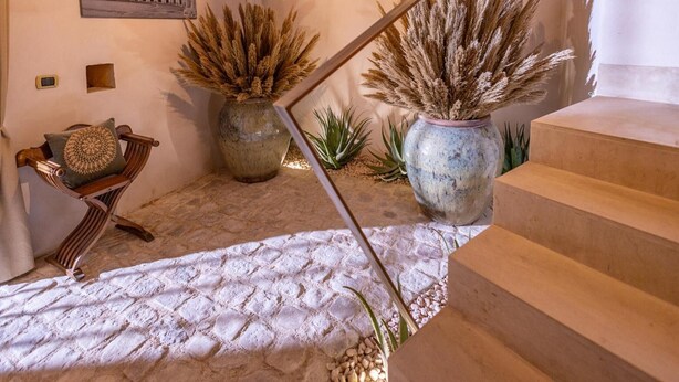A staircase with a metal handrail, a bench with a cushion, and two large pots with dried plants. - Sinatra Suite Apartment with Private Terrace, Wi-Fi and Air Conditioning (Ispica)