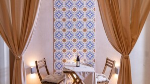 A dining area with a table set for two, a bottle of wine, and a patterned wall. - Sinatra Suite Apartment with Private Terrace, Wi-Fi and Air Conditioning (Ispica)