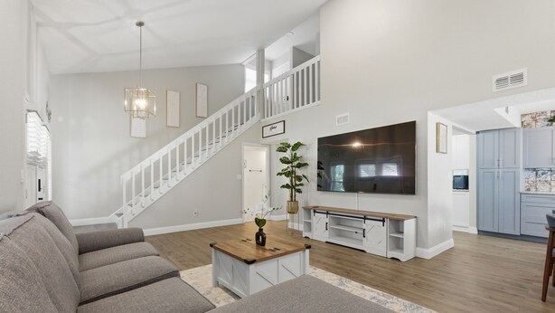 A modern living room with a sofa, coffee table, and TV. - Levine's Spacious Clearwater Retreat with Pool (Clearwater)