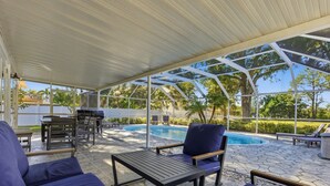 A covered outdoor area with a pool, seating, and a grill. - Levine's Spacious Clearwater Retreat with Pool (Clearwater)