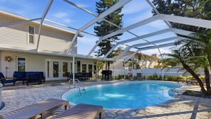 A swimming pool with a covered patio area, lounge chairs, and a barbecue setup. - Levine's Spacious Clearwater Retreat with Pool (Clearwater)