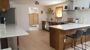 Uma cozinha moderna com ilha central, armários de madeira e banquetas.