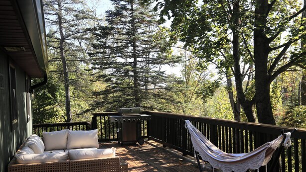 A wooden deck with a wicker sofa, a hammock, and a grill. - Larkspire I Sleepy Hollow Lake I Beach & Firepit (Athens)