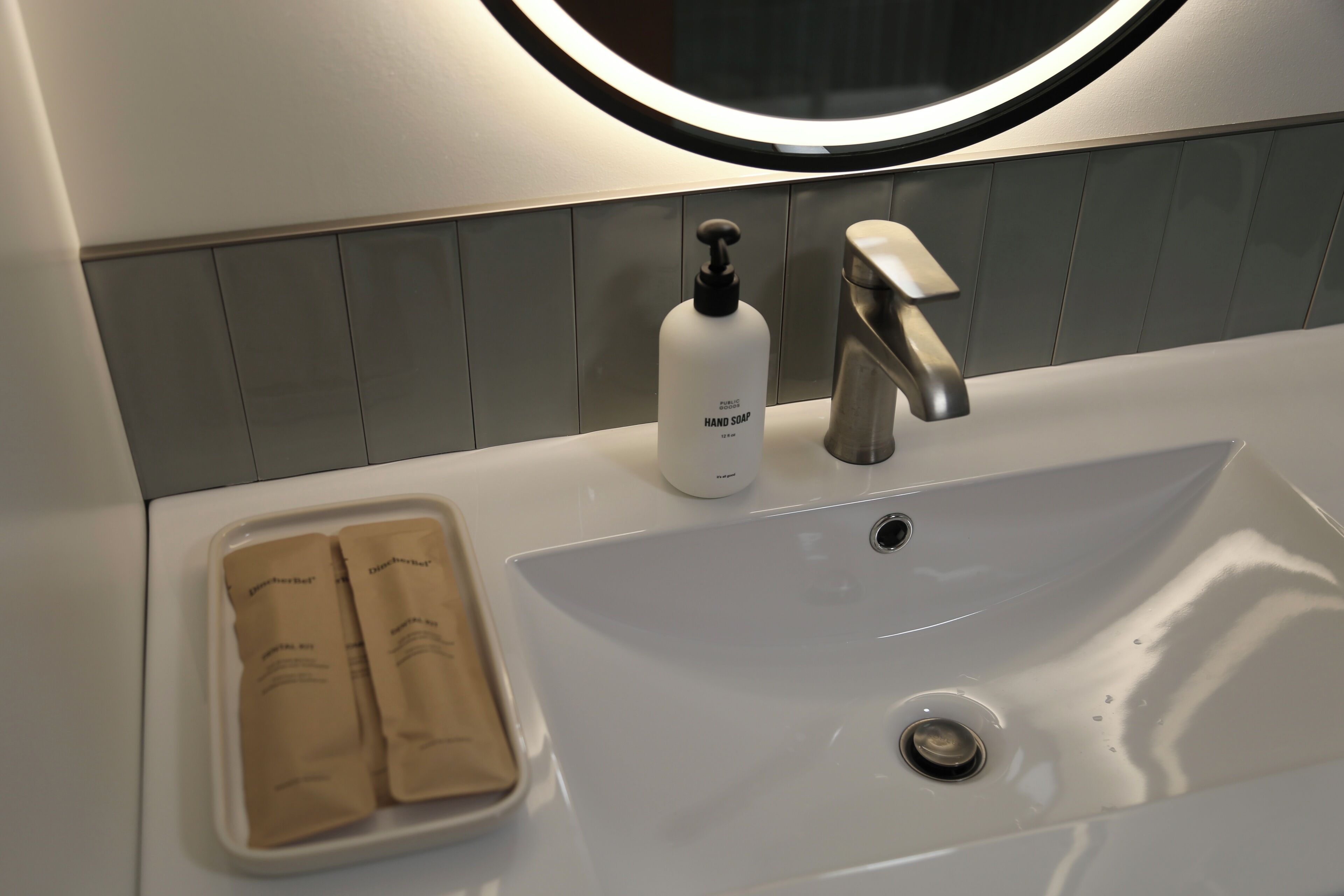 Ein modernes Badezimmer mit einem weißen Waschbecken, einer Seifenspender und einem Handtuchhalter mit zwei Handtüchern.