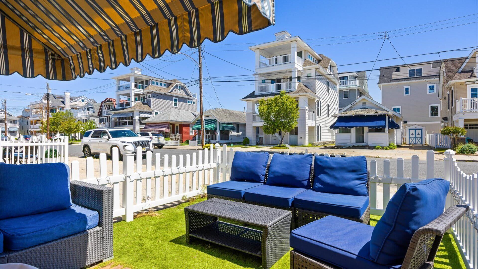 A patio with wicker furniture and a striped awning.