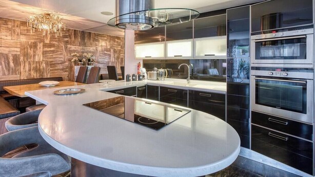 A modern kitchen with a central island, built-in ovens, and a dining area with a chandelier. - Sea-View Terrace Maisonette, steps from Paceville! (Swieqi)