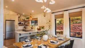 Een moderne keuken met een centraal eiland, roestvrijstalen apparatuur en een eethoek met een houten tafel gedekt voor zes personen.