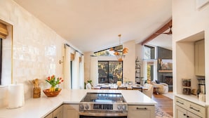 Een moderne keuken met een centraal eiland, een eetgedeelte met uitzicht en een open haard.