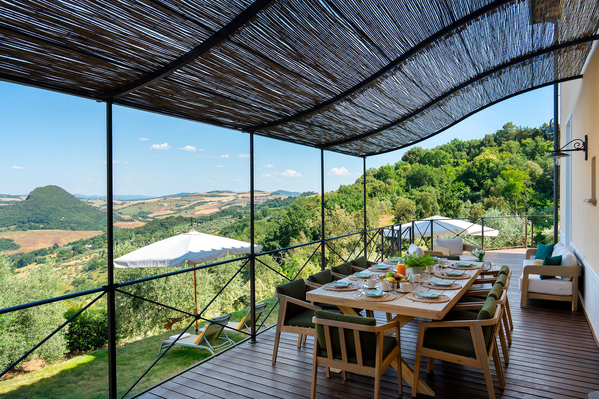 Una terrazza con un tavolo apparecchiato per la cena, affacciata su un panorama suggestivo.