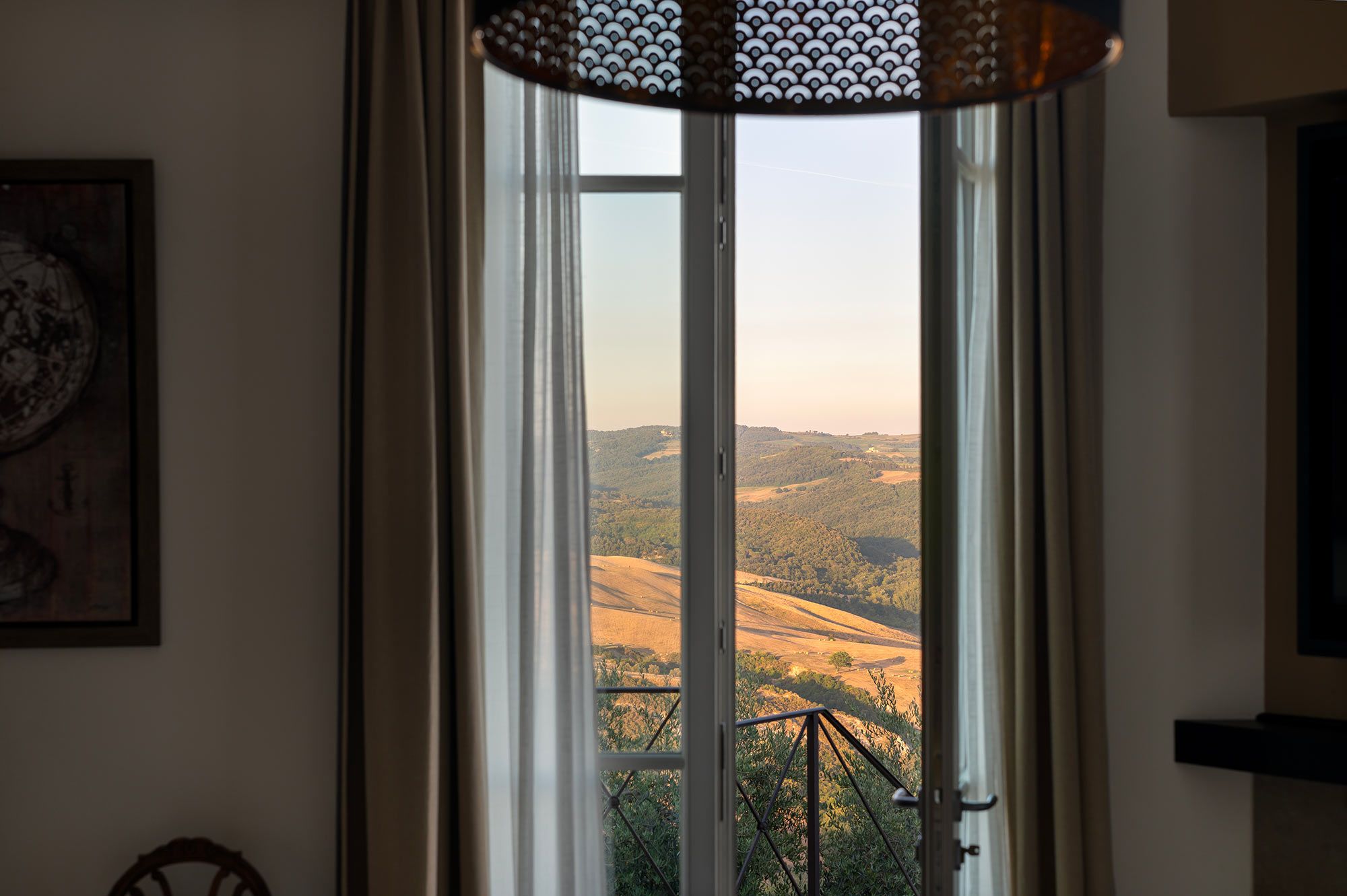 Ein Zimmer mit einem großen Fenster und Blick auf eine hügelige Landschaft.