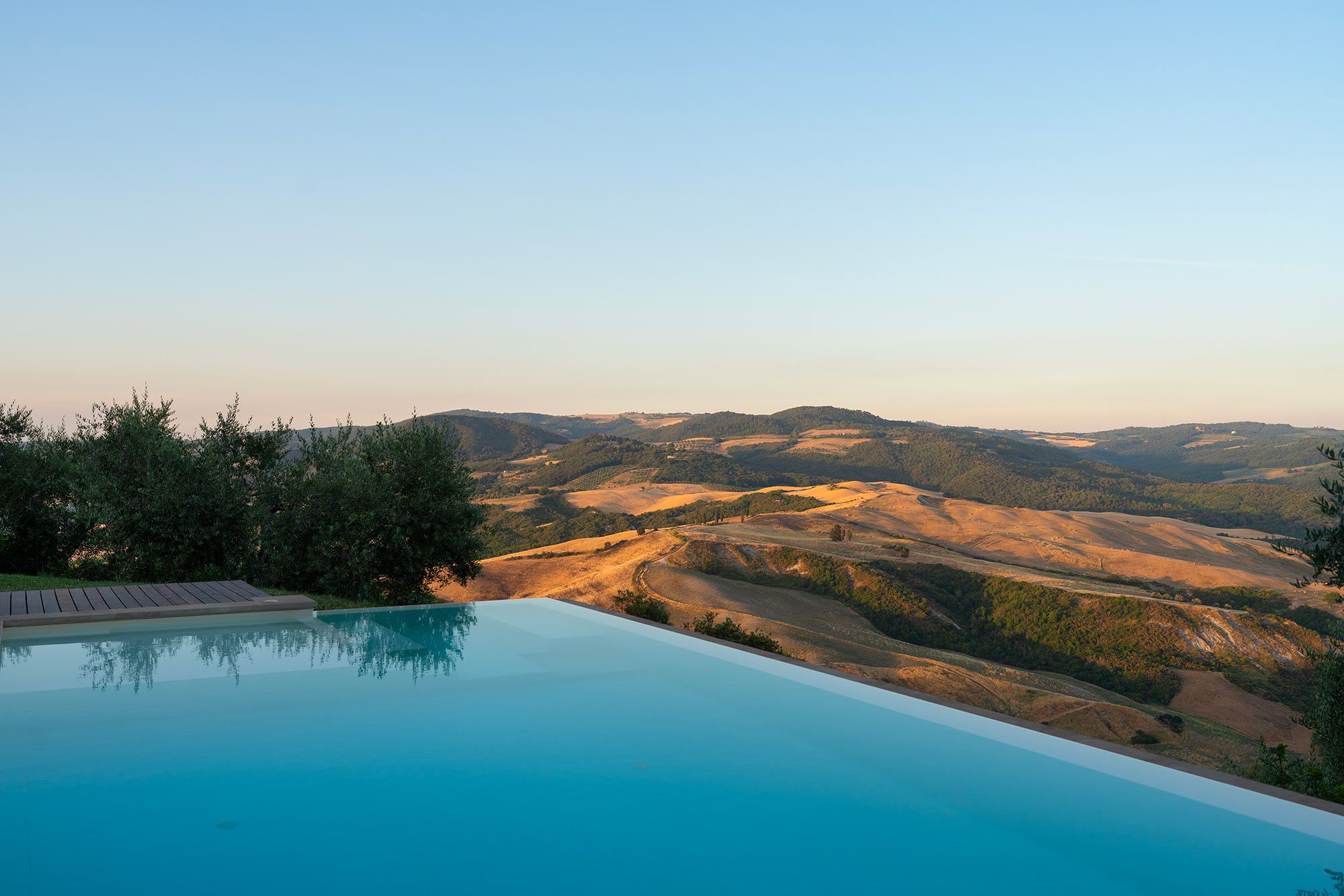 Une piscine offrant une vue sur des collines verdoyantes et un ciel dégagé.