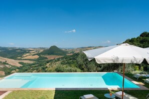 A swimming pool with a view of a hilly landscape and a white umbrella. - Villa Francesca 10, Emma Villas (Volterra)