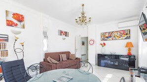 A modern living room with a glass table, a brown sofa, and a chandelier. - Exceptional location, stunning sea view. Modern 48 m² apartment, center, 17 m² terrace. (Canet Plage)