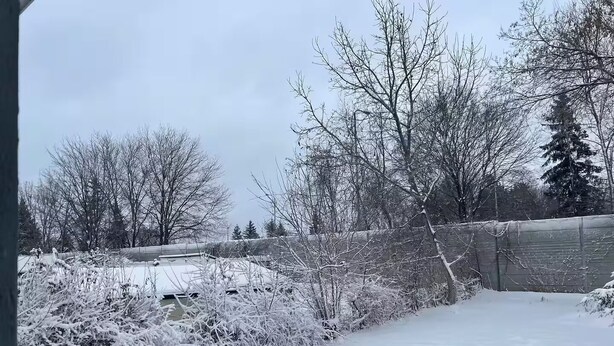 Ein verschneiter Außenbereich mit einer Holzterrasse und einem Metallzaun.