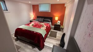 Ein Schlafzimmer mit einem Bett, Nachttischen, einem Schreibtisch und einem Sessel.