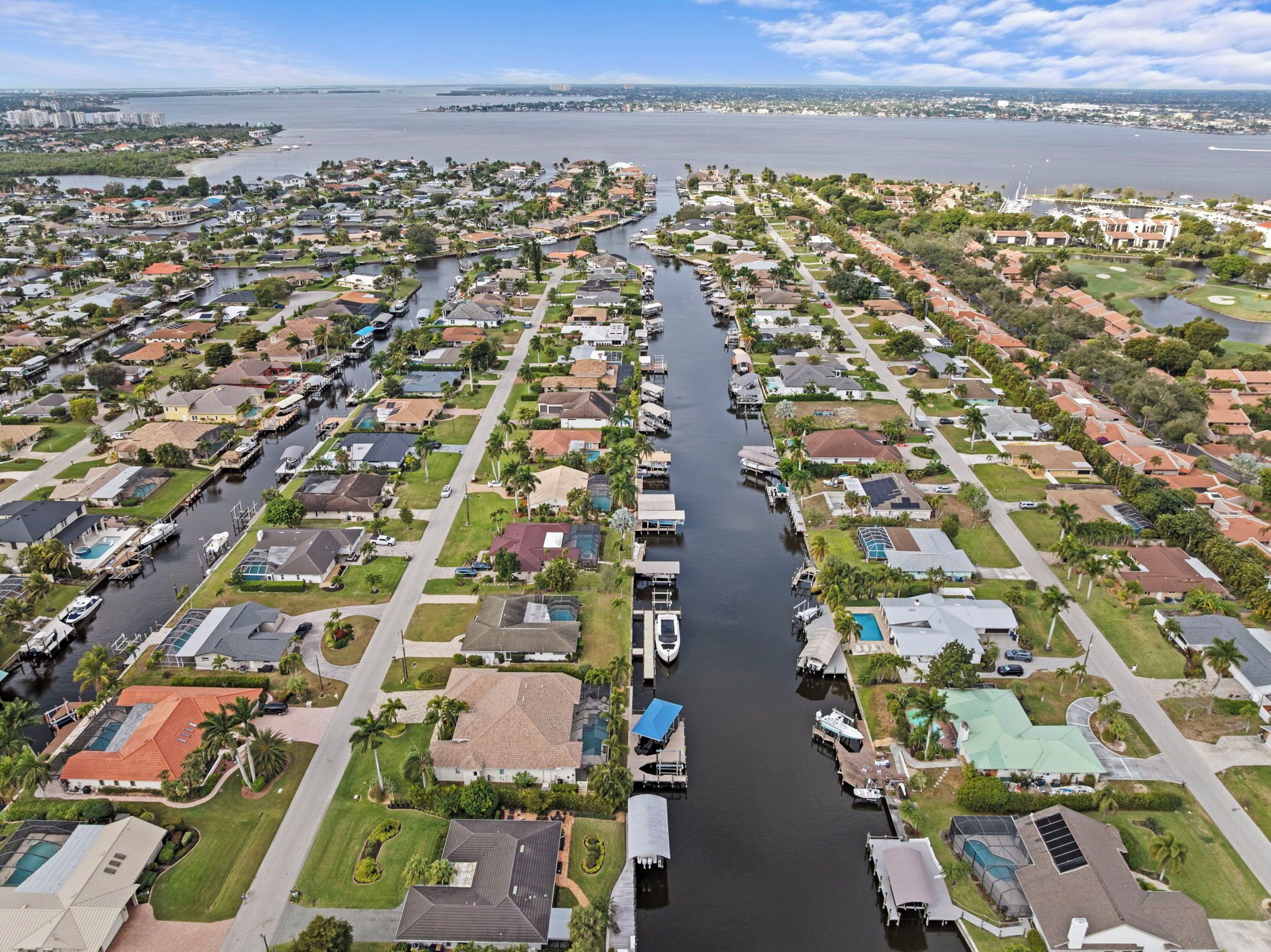 Luchtbeeld van een woongebied met een gracht erdoorheen, omringd door huizen en boten.