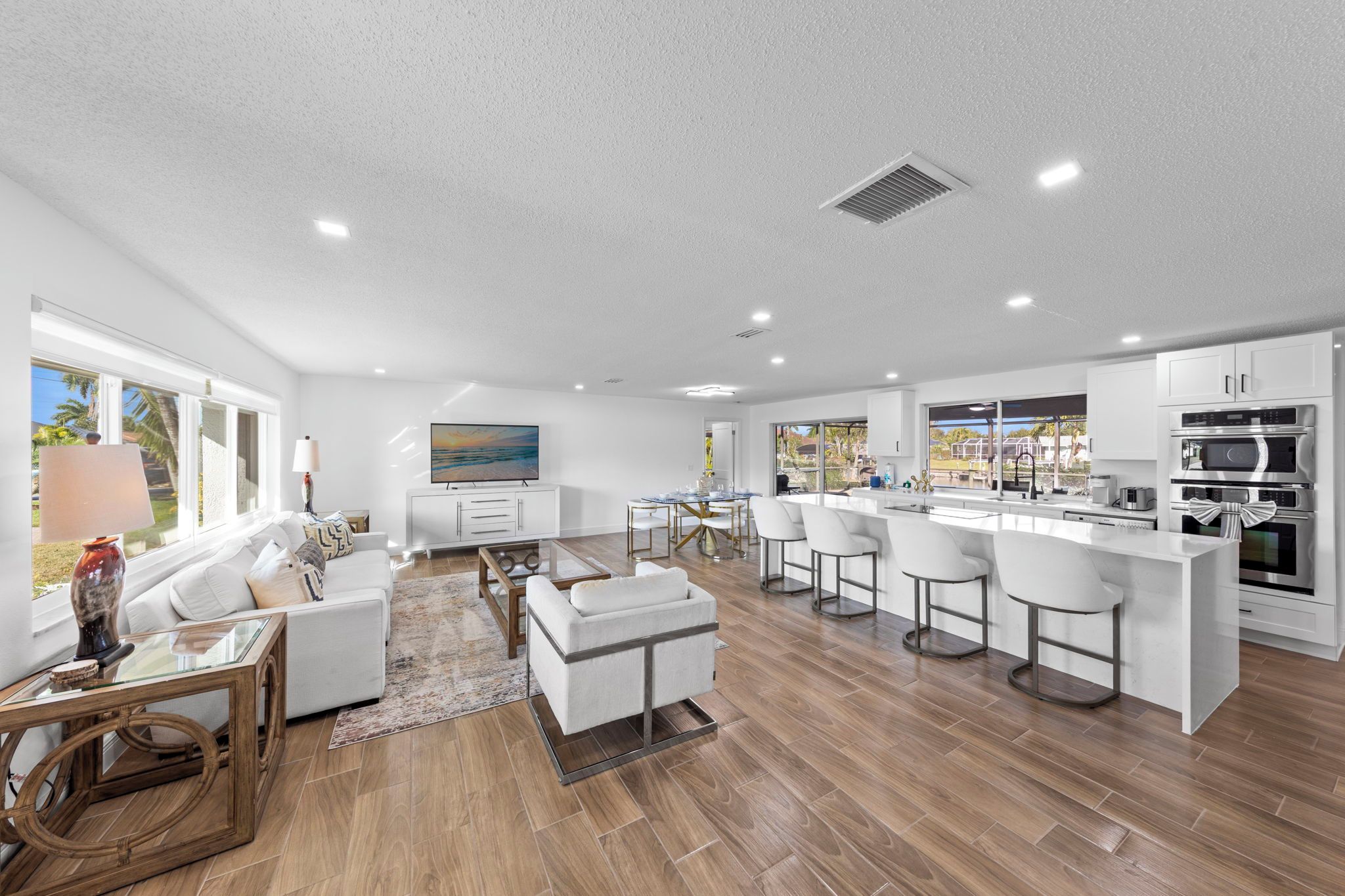 A modern kitchen with a bar area, white cabinetry, and a large island with bar stools.