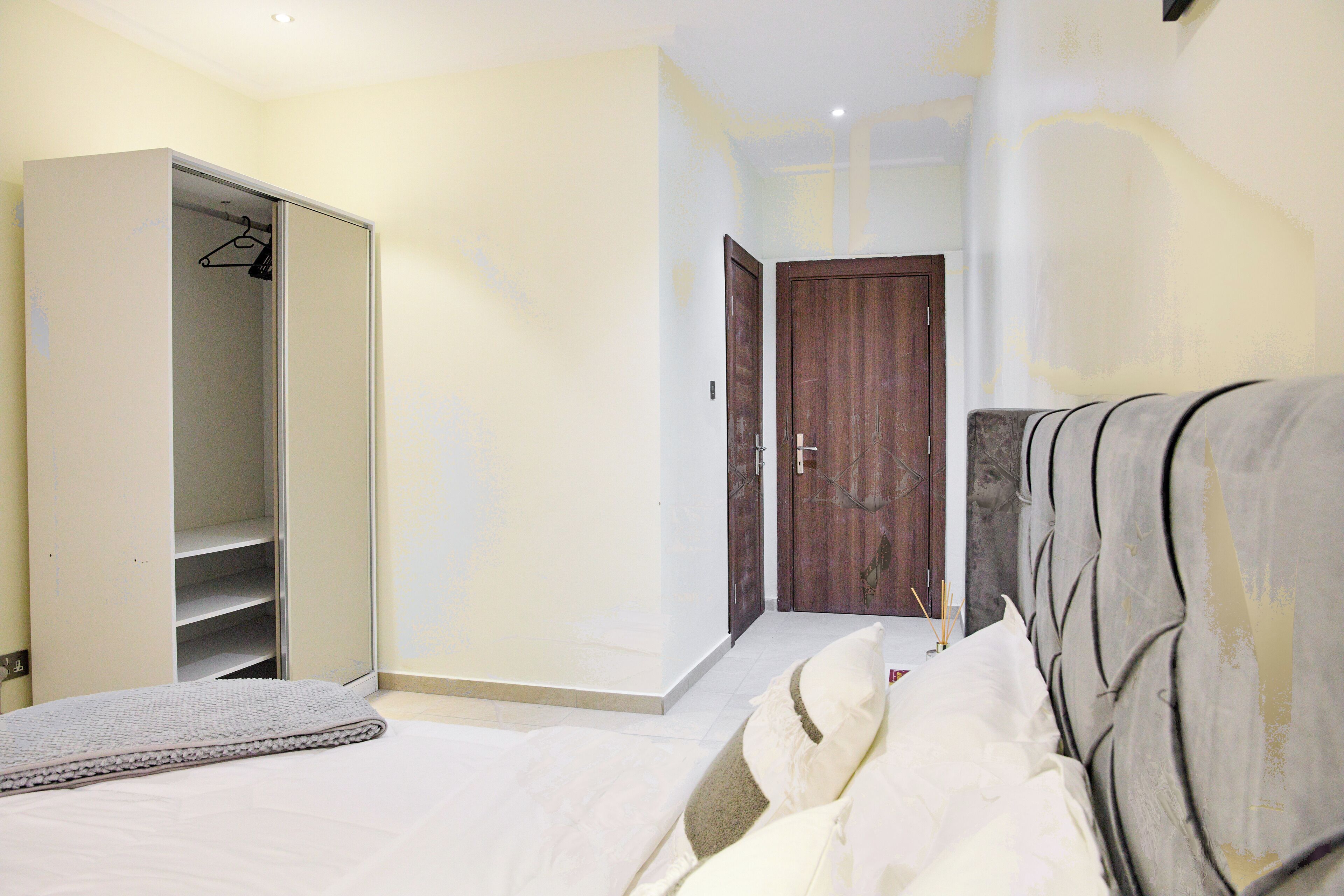 A bedroom with a bed, a wardrobe, and a door leading to another room.