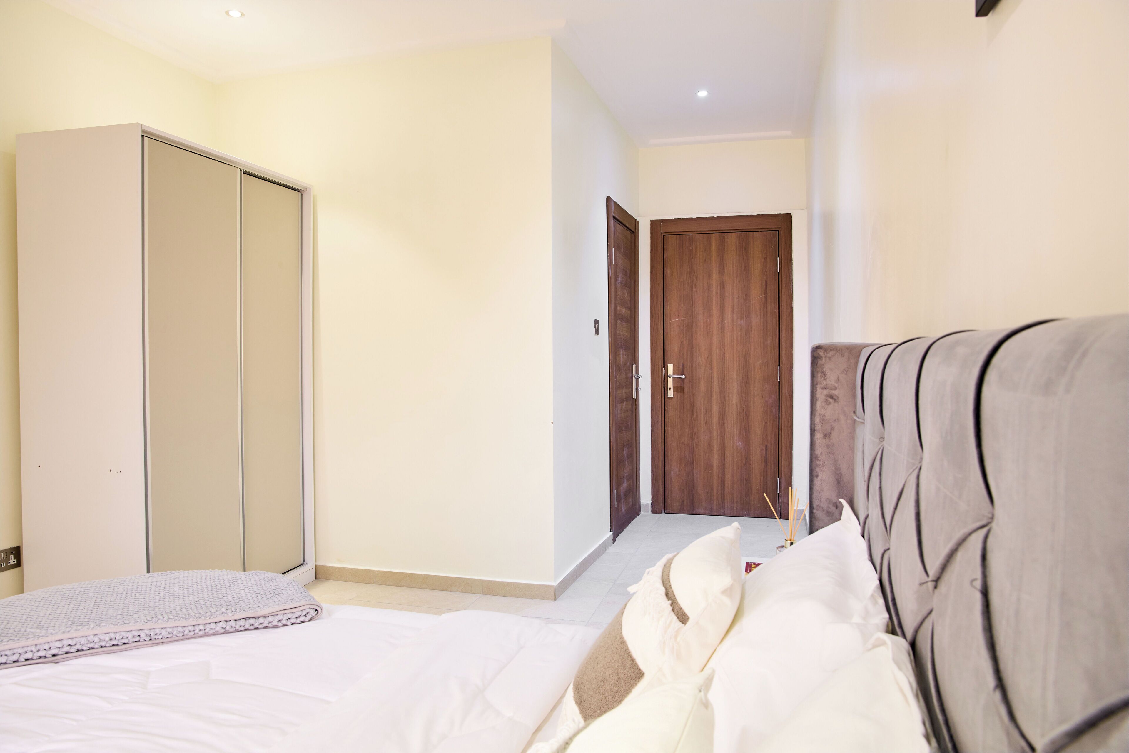 A bedroom with a bed, a wardrobe, and a door leading to another room.
