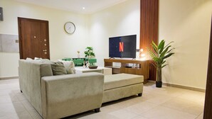 Una sala de estar moderna con un sofá, un televisor, un reloj y una planta en maceta.