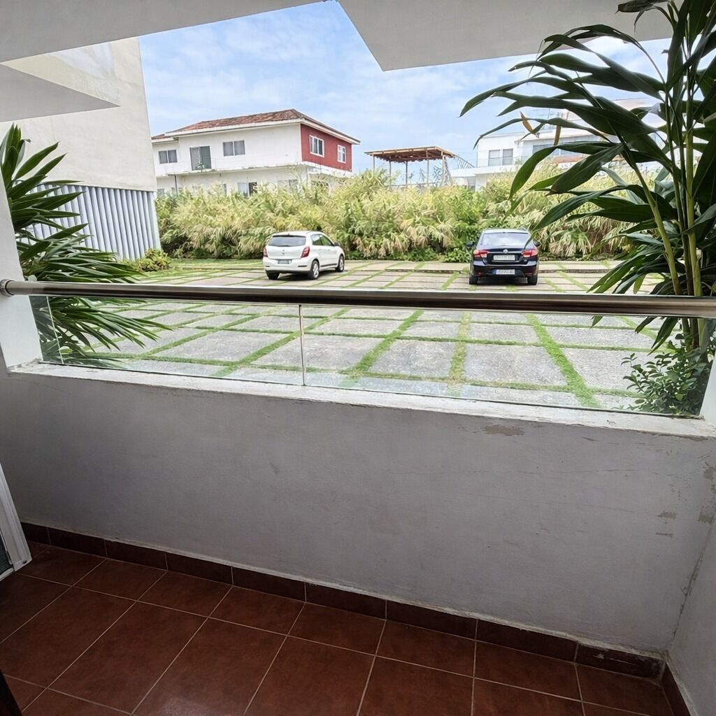Ein Balkon mit Blick auf geparkte Autos und ein Gebäude im Hintergrund.