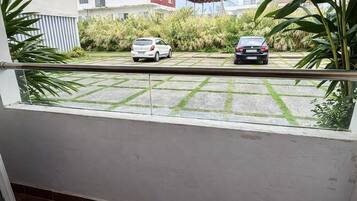Un balcón con vista a coches estacionados y un edificio al fondo.