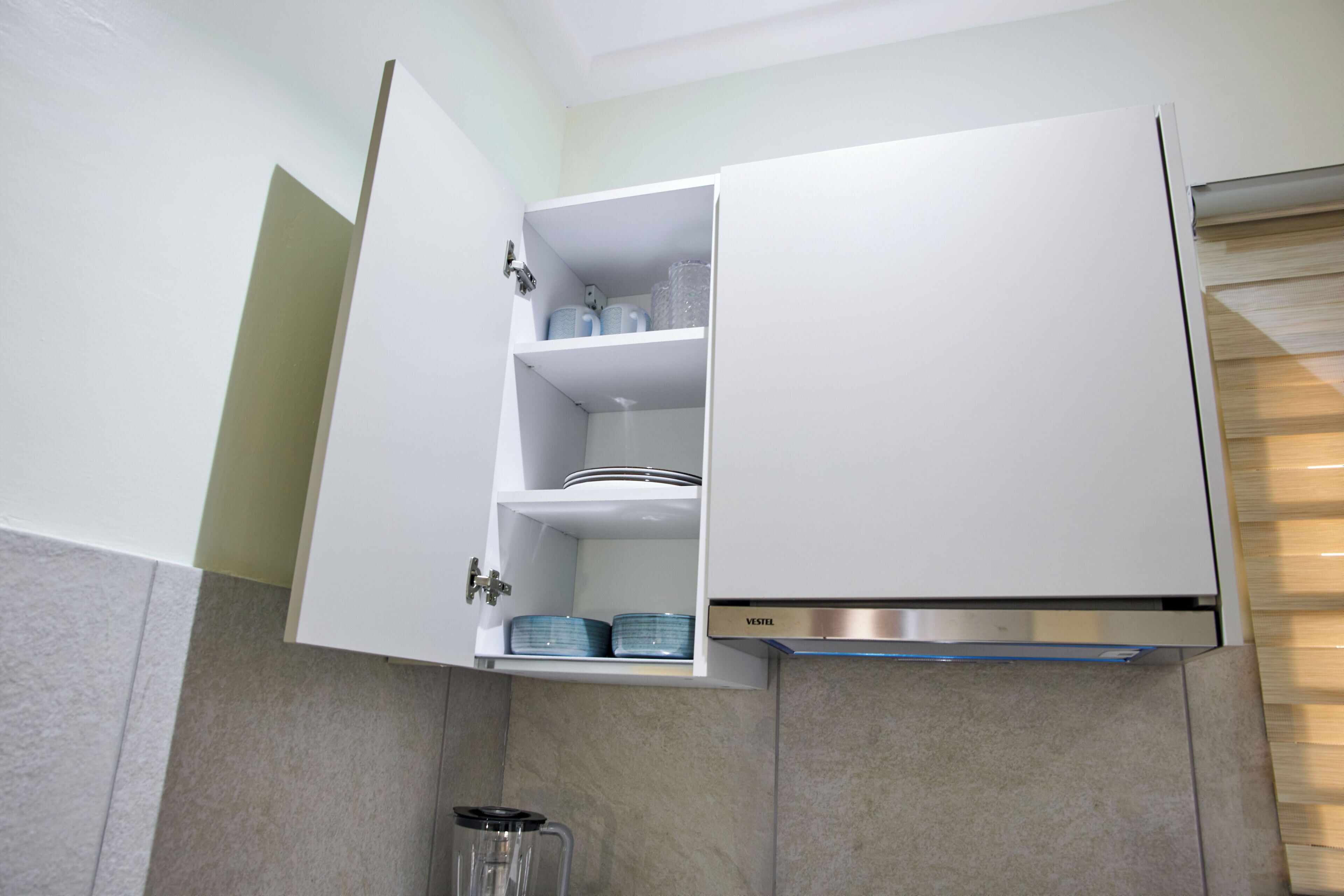 A kitchen with white cabinets, a stainless steel range hood, and a built-in dishwasher.