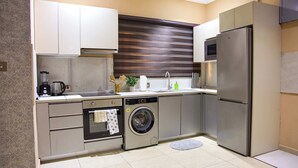 Una cocina moderna con electrodomésticos de acero inoxidable, horno empotrado, lavadora y refrigerador.